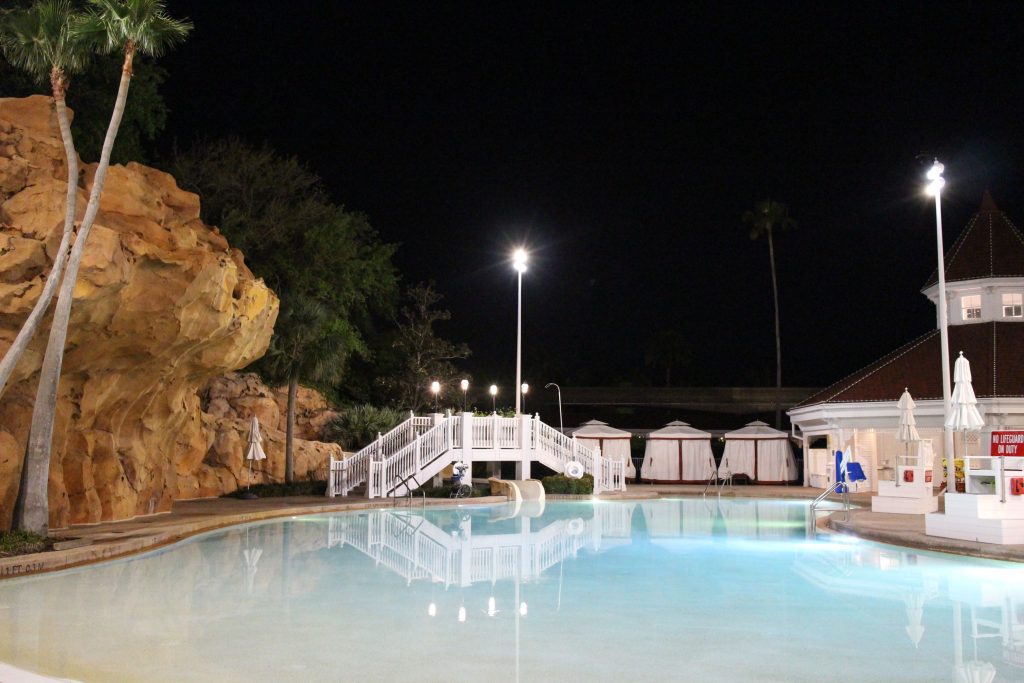 A peaceful, blue pool at night with a rock structure next to it.