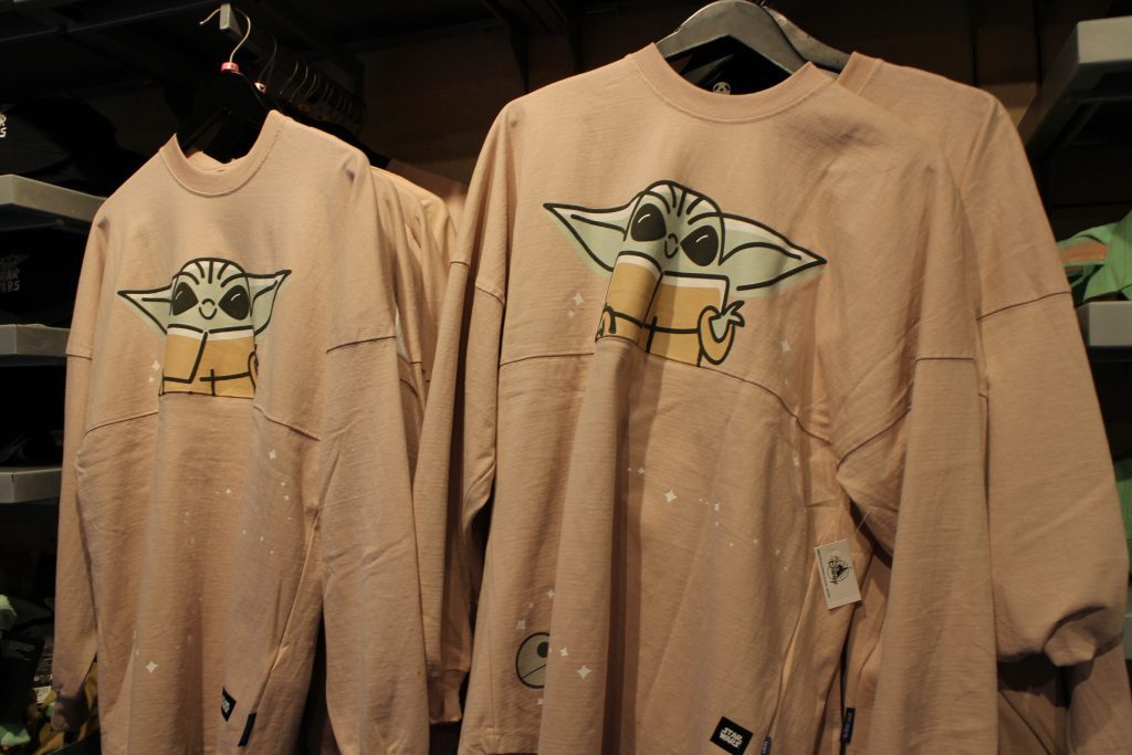 A tan, long sleeve shirt with Grogu, baby Yoda, from The Mandolorian on it at Disney World.