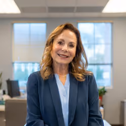 Portrait of a smiling woman in a navy blazer in an office