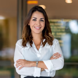 Portrait of a smiling woman in a white shirt with her arms crossed