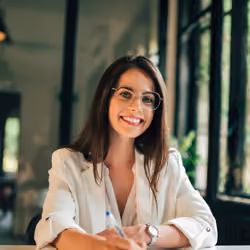 Portrait of a smiling woman with glasses at a desk
