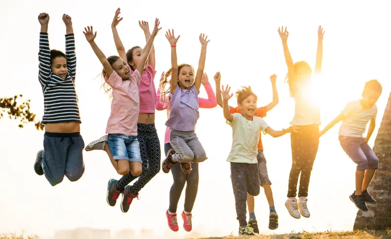 Group of children jumping joyfully in the air at sunset