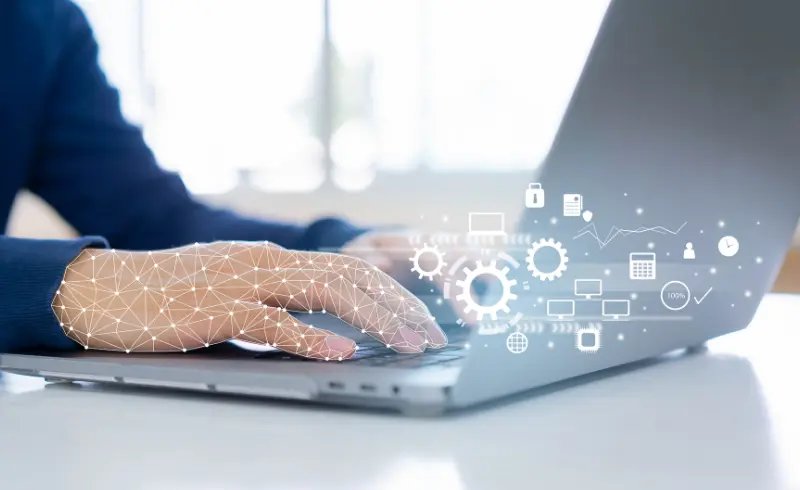Hand typing on a laptop with a network of digital icons overlaid