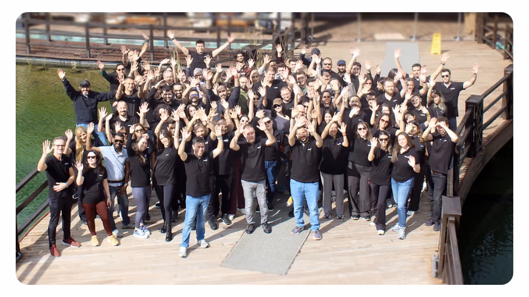 Large group of Sestek employees waving together on a wooden bridge