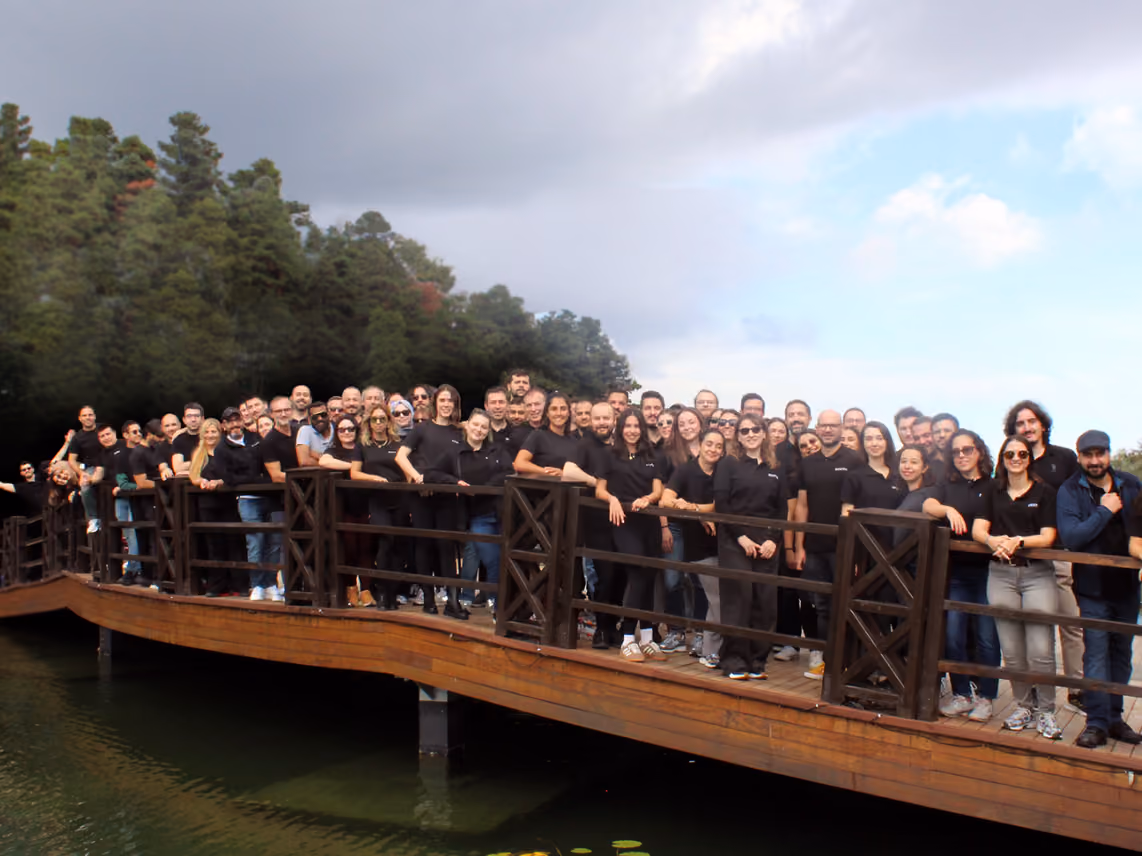Sestek employees posing together on a wooden bridge over a lake