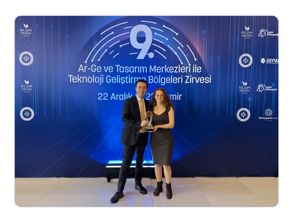 Two Sestek employees holding an award at the R and D and Design Centers Summit