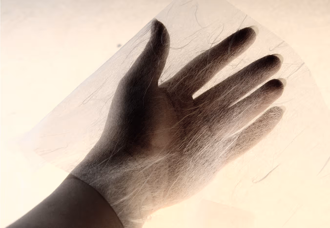 Picture of a hand holding the tissue-weight Unryu paper, showcasing the silvery flowing fibers in the material.