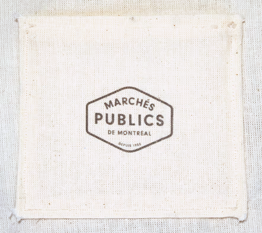 Macro shot of the pocket detail on the back of the mushroom bag, with the logo of Marchés Publics de Montréal printed on it.