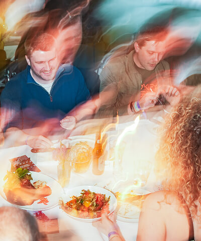 blurred photo of people sitting around table eating and laughing