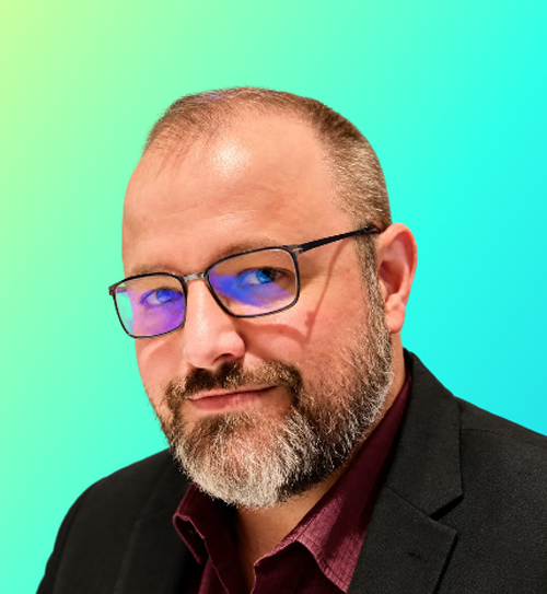 Middle-aged man with a beard and blue shirt smiling against a gradient turquoise background.