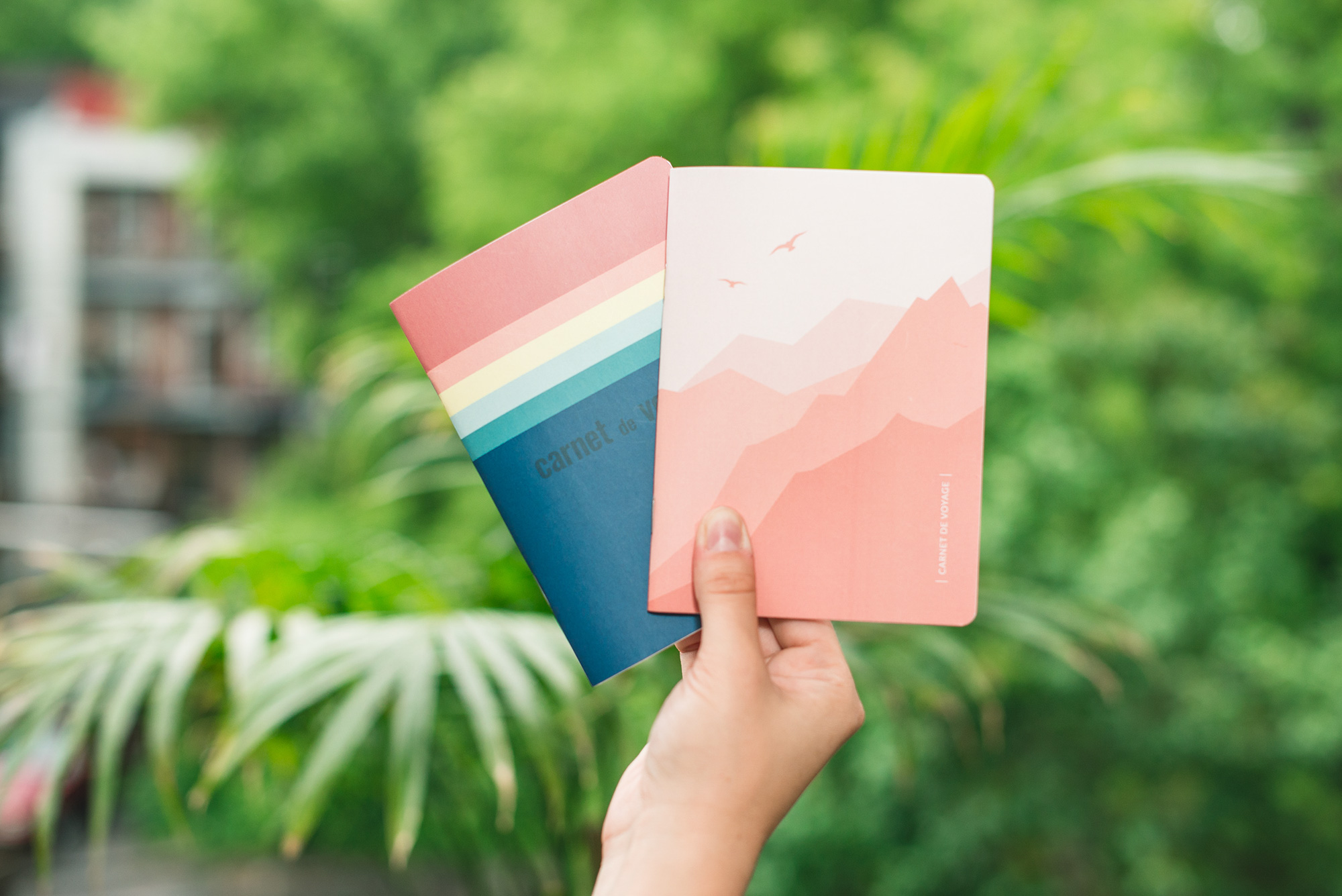 Carnets de voyage Les insécables tenus devant un feuillage