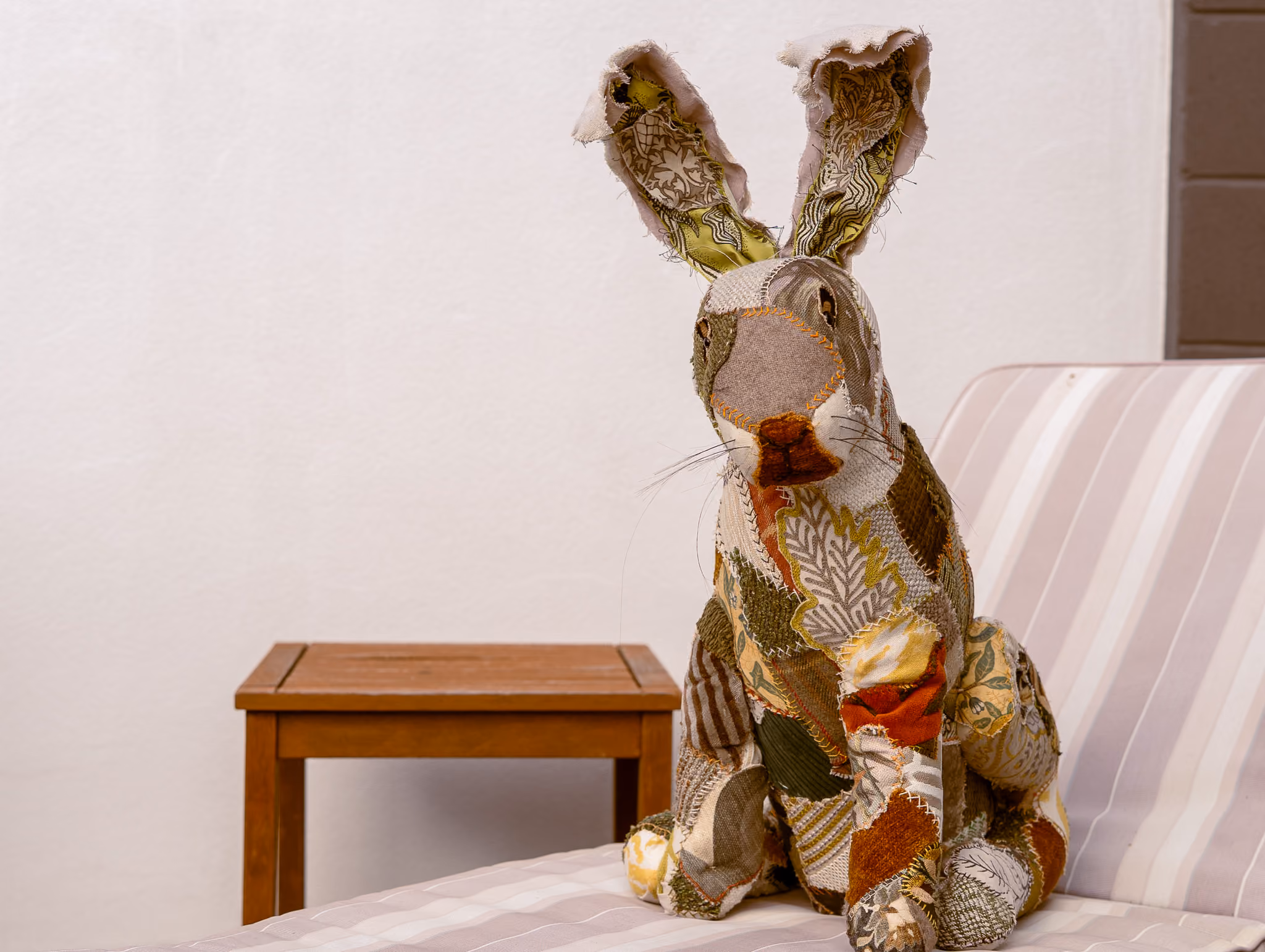 Archie the patch work rabbit mascot on a chair