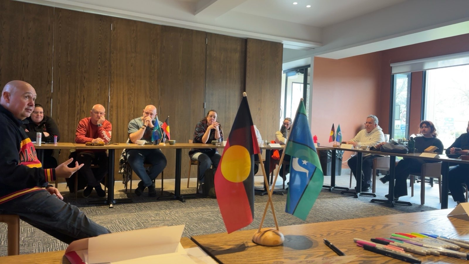 Shawn Andrews seated in a Be BRAVE Feel SAFE room, the Aboriginal and Torres Strait Islander flags in the foreground
