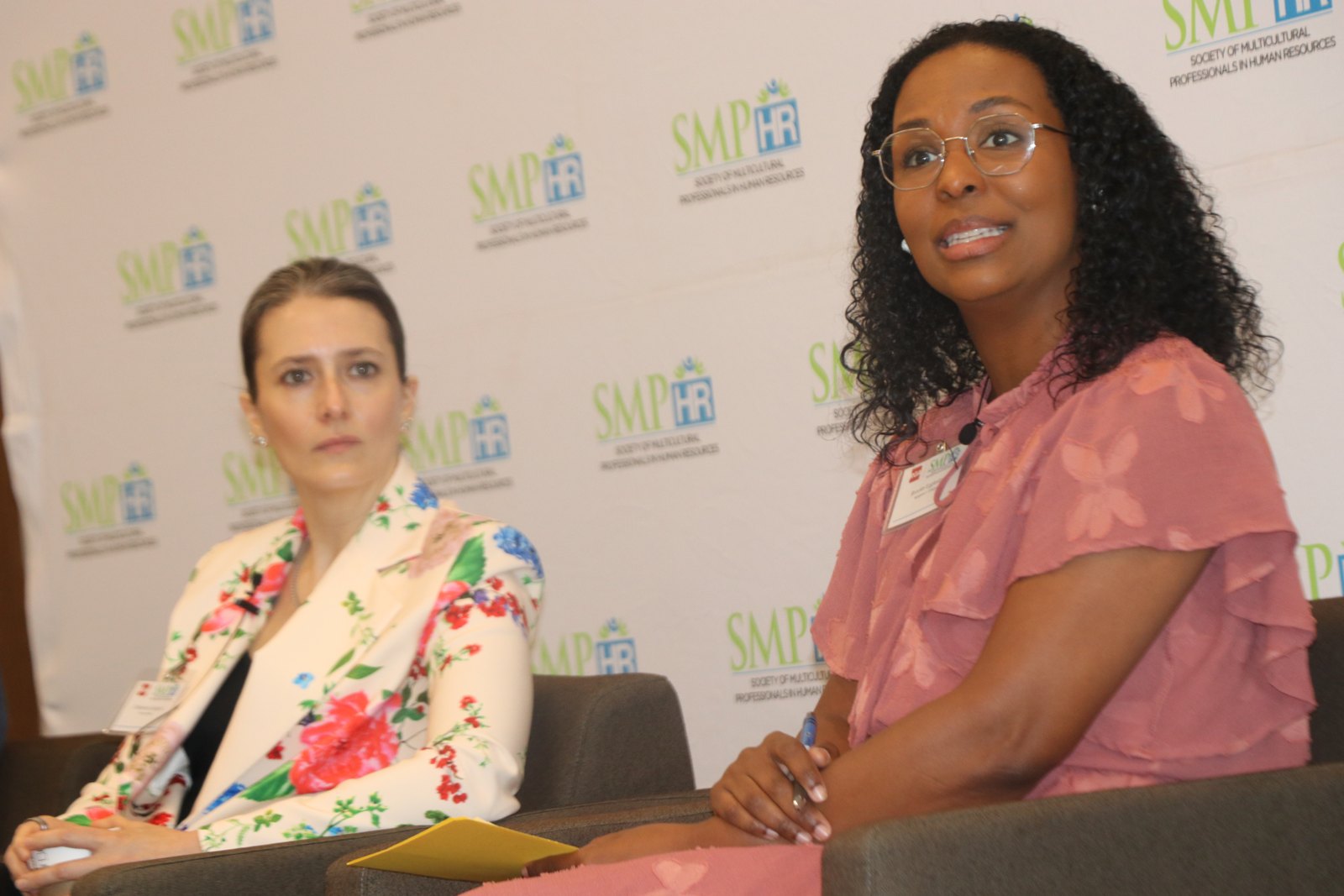 Two women panelists in discussion, one in floral blazer speaking