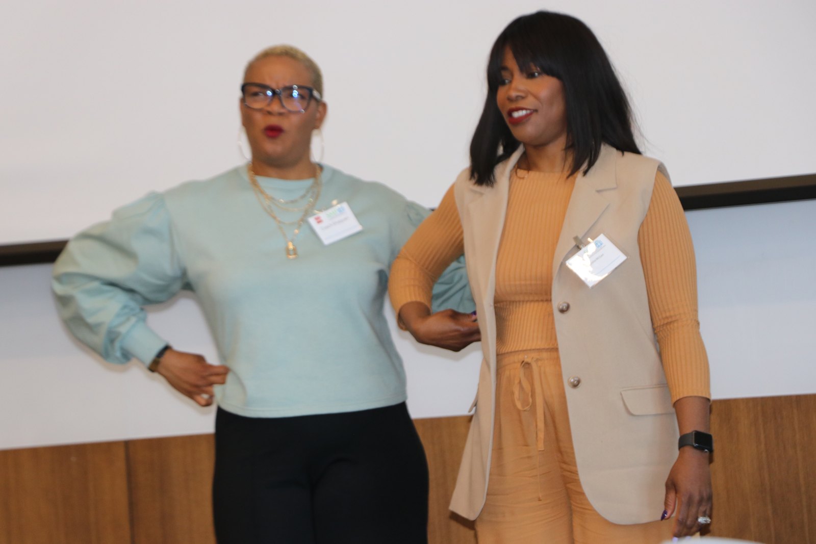 Two professional women with name badges standing together on stage