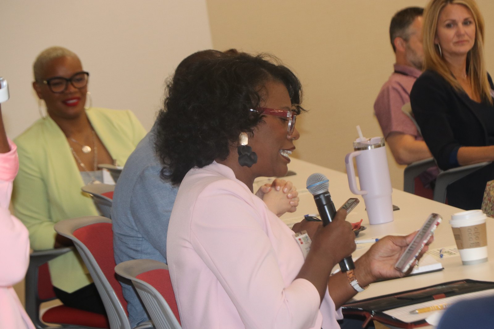 Woman speaking at panel with other panelists seated at table