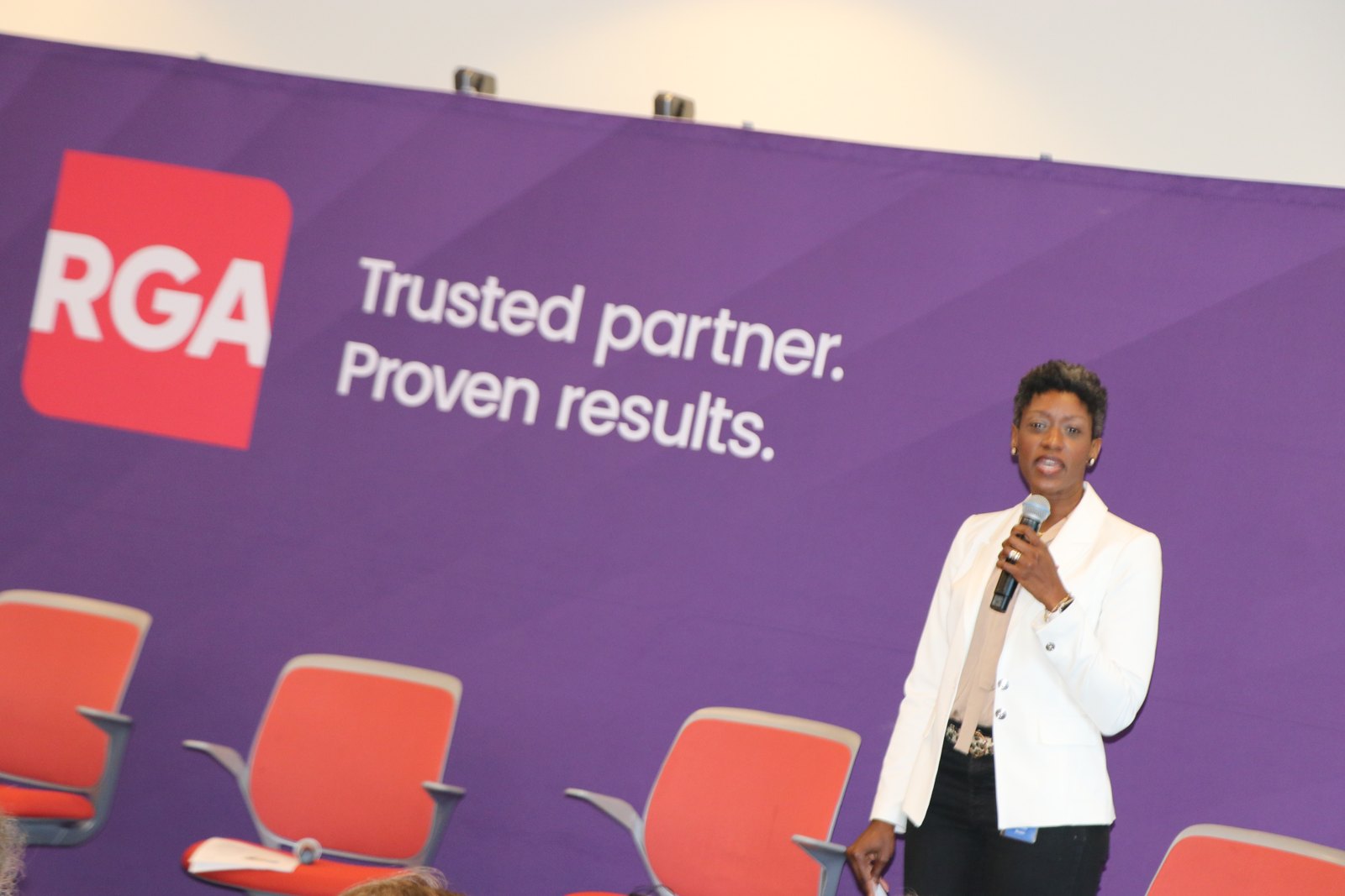 Woman speaking at podium against RGA-sponsored event backdrop
