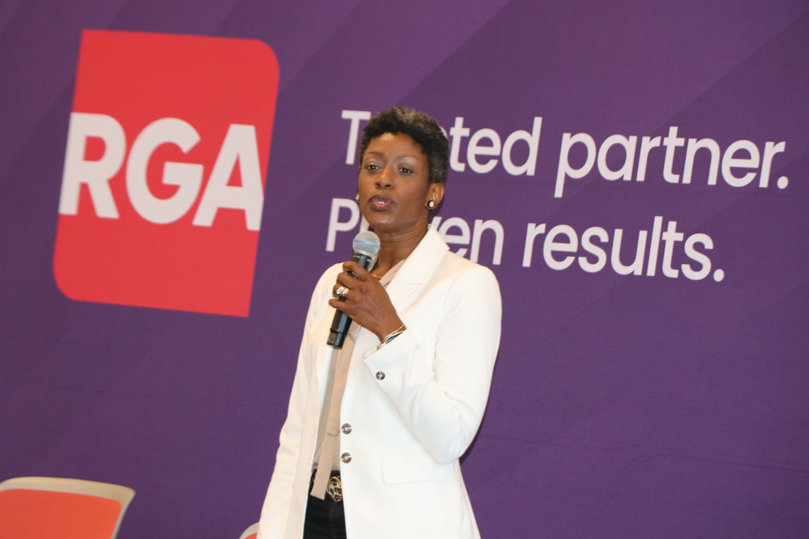 Woman speaker at RGA partnership event with branded backdrop