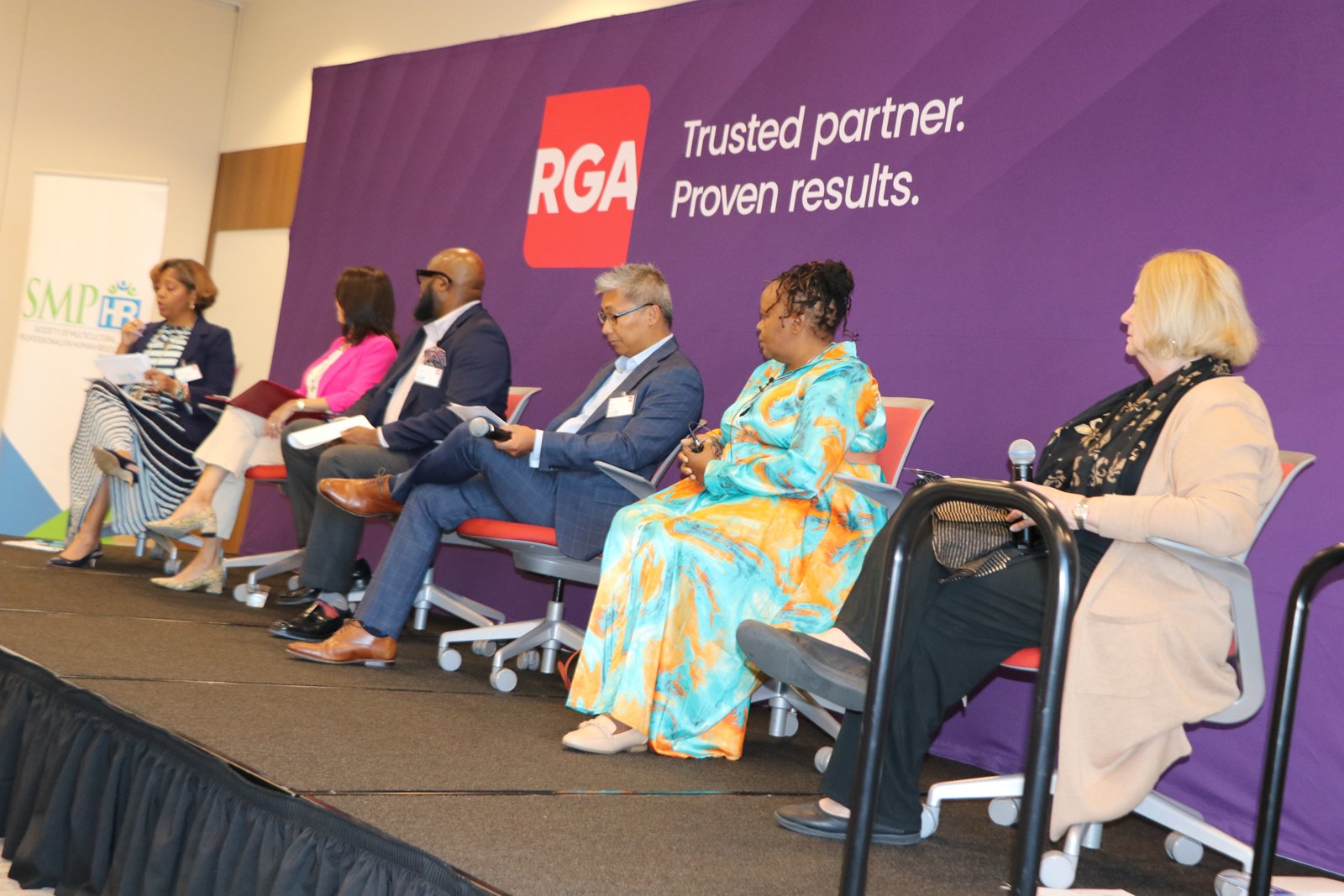 HR professionals in panel discussion against RGA branded backdrop