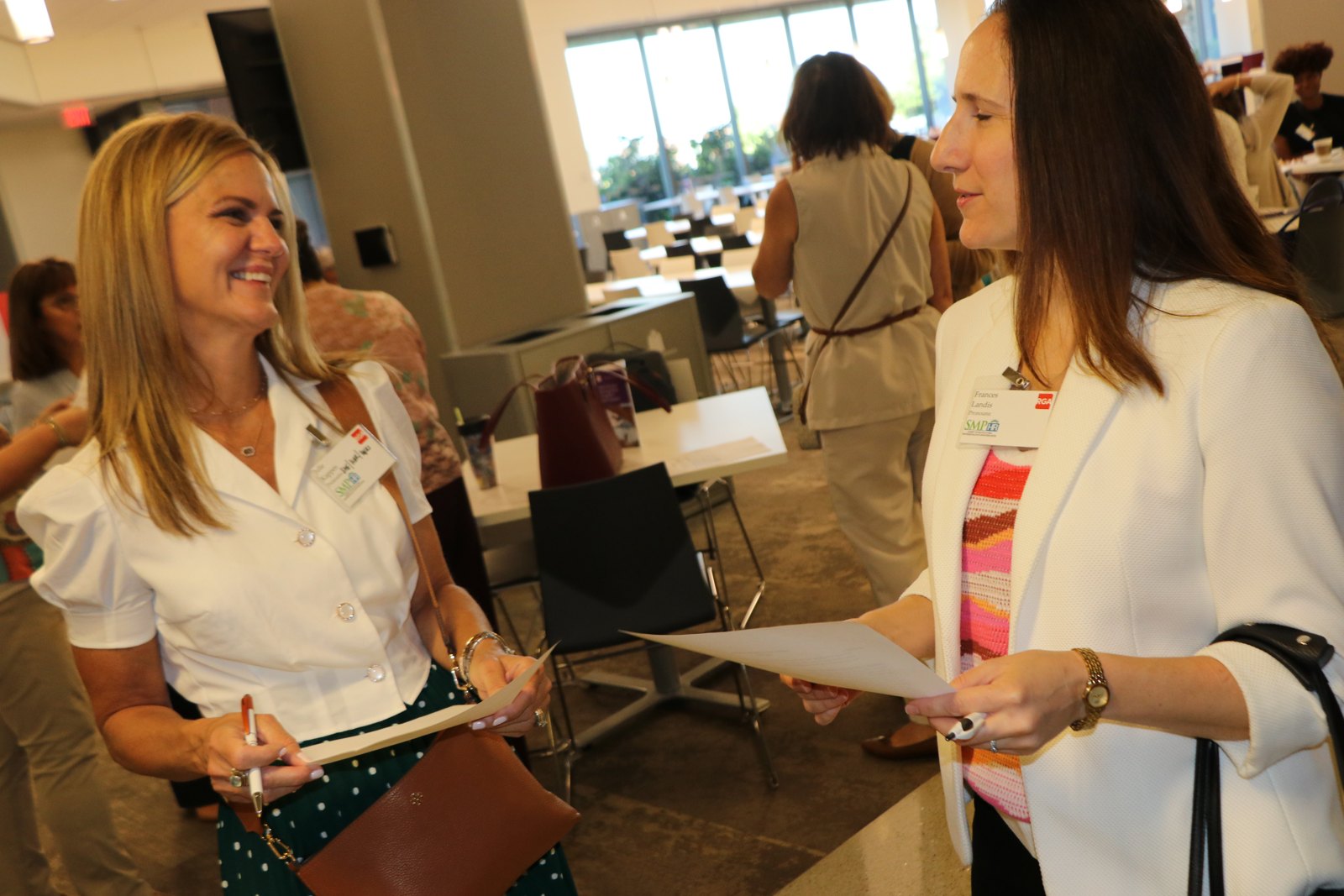 Two women in professional attire talking at an SMPHR event