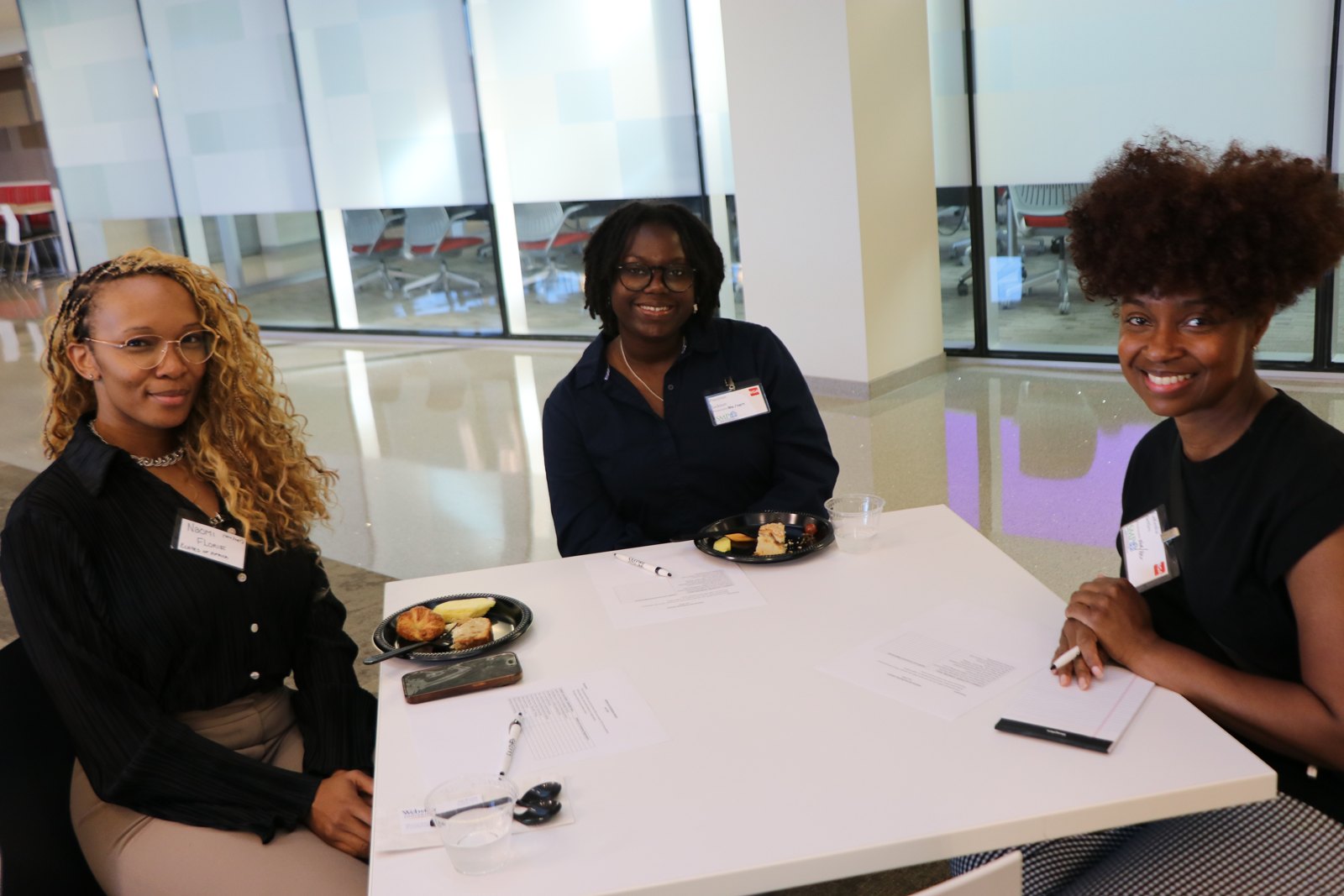 Three women at SMPHR networking meal with food and badges