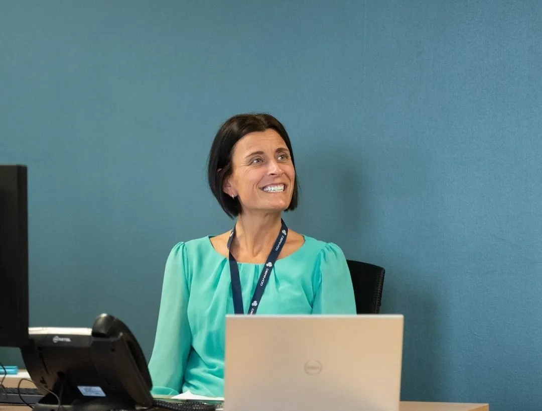 A colleague smiling from behind a desk