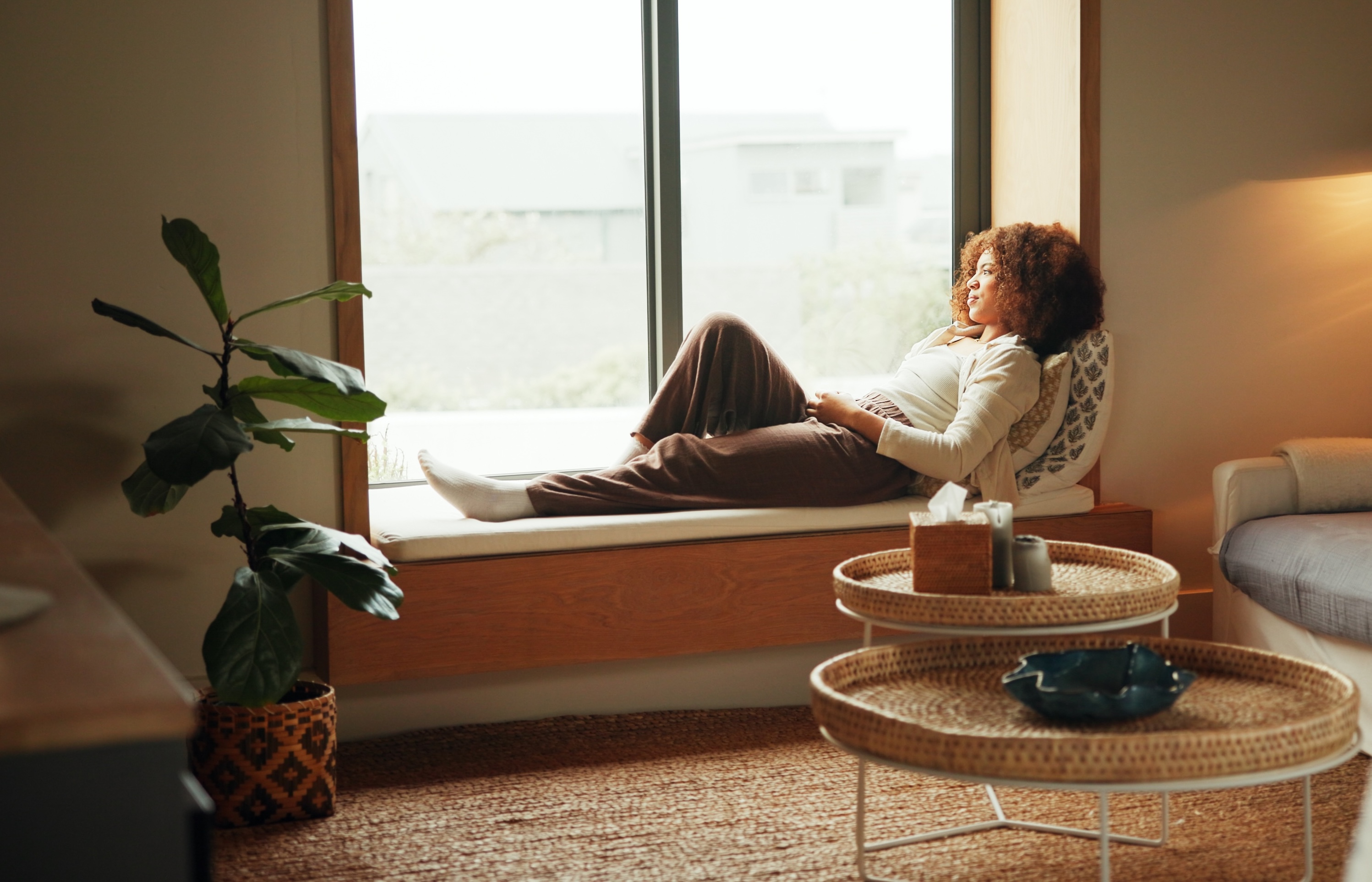 Frau entspannt in einem ruhigen Wohnraum mit natürlichem Licht – modernes Feng Shui, Raumwirkung und Regeneration bei Stress, Erschöpfung und Burnout.