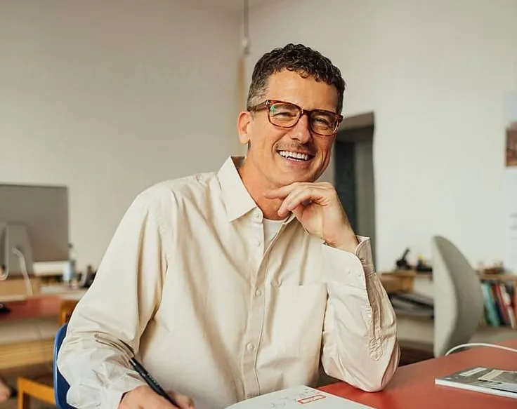 Un homme souriant à son bureau, dans un espace de travail lumineux