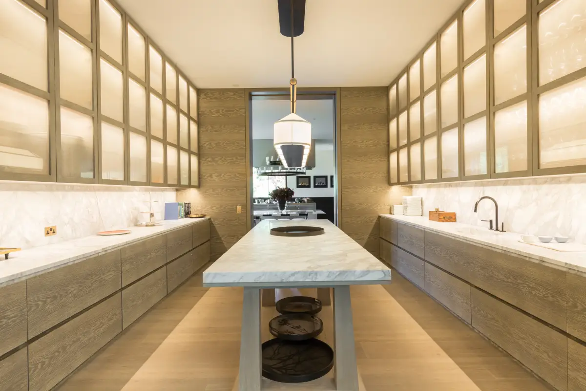 Villa A, Londres, vue intérieure cuisine avec une longue table en marbre au centre de la pièce