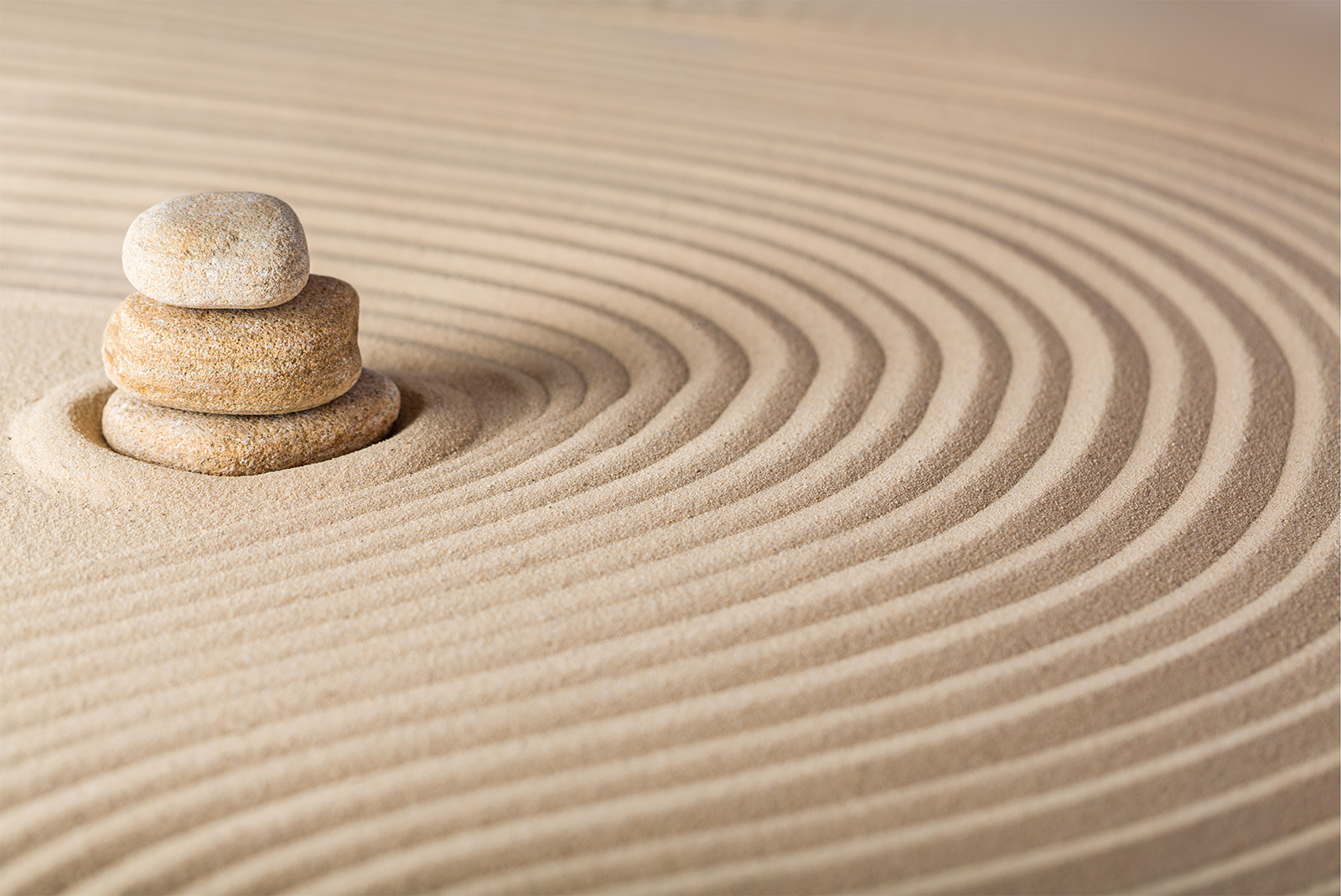 3 Steine übereinander angeordnet auf Sand mit Kreisen.