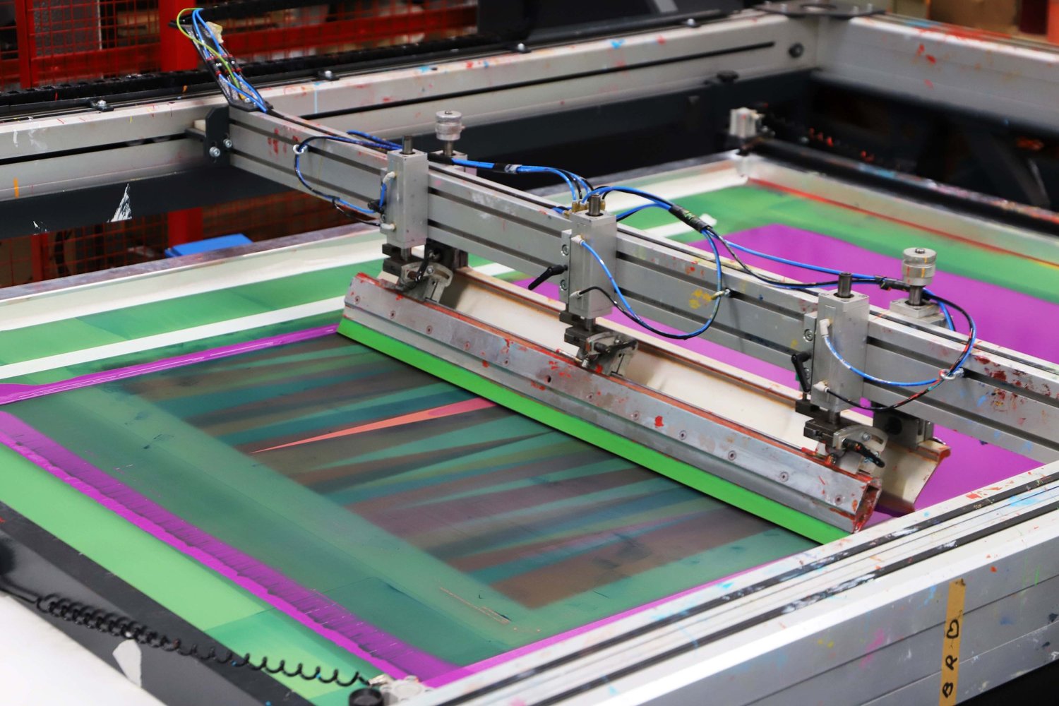 Screenprinting Odili Donald Odita's Firewall at Atelier JI — a squeegee pulling colour across a green and magenta screen bed.