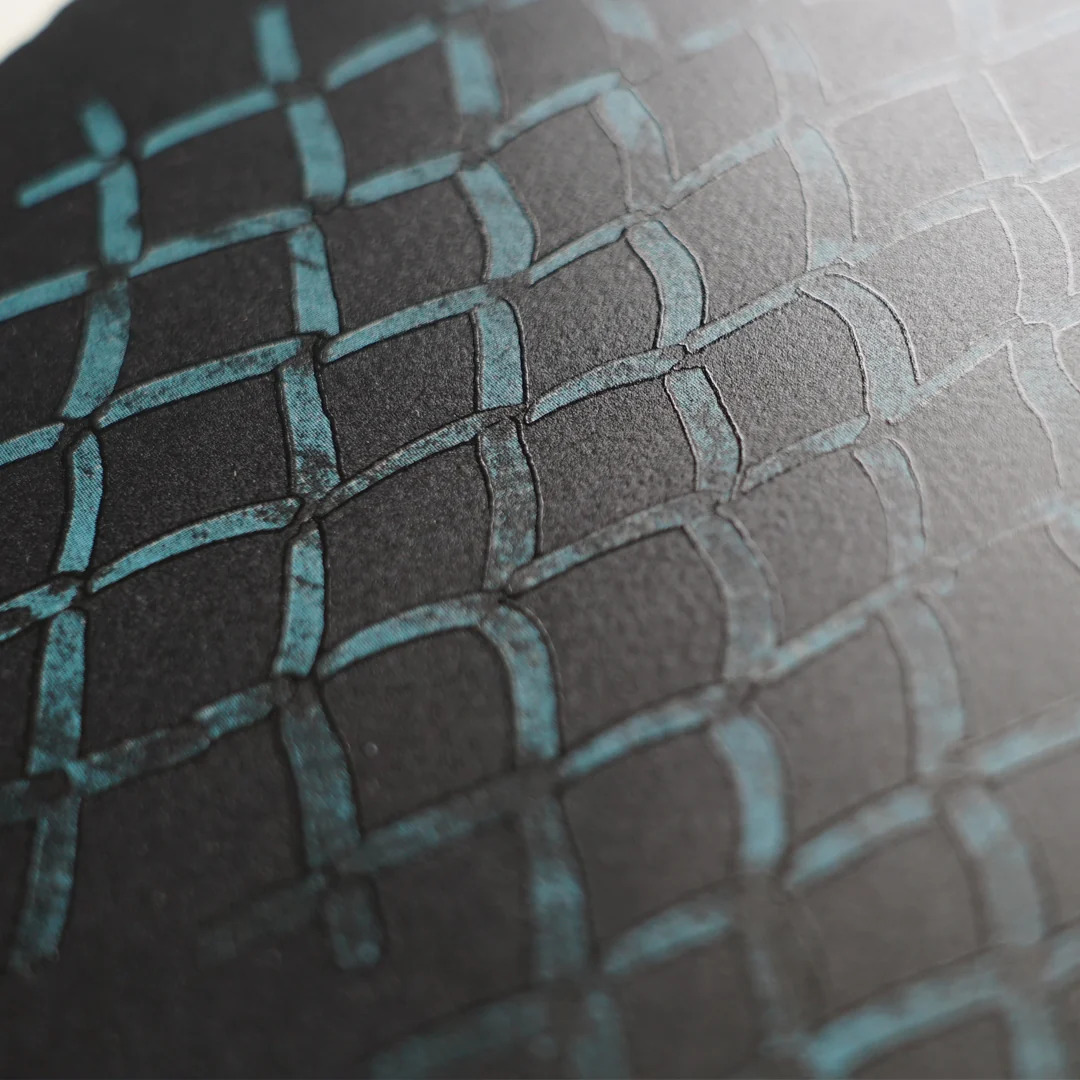 A raking-light detail of Mona Hatoum's The Blues, the teal chain-link pattern raised in high-build ink above the black ground.