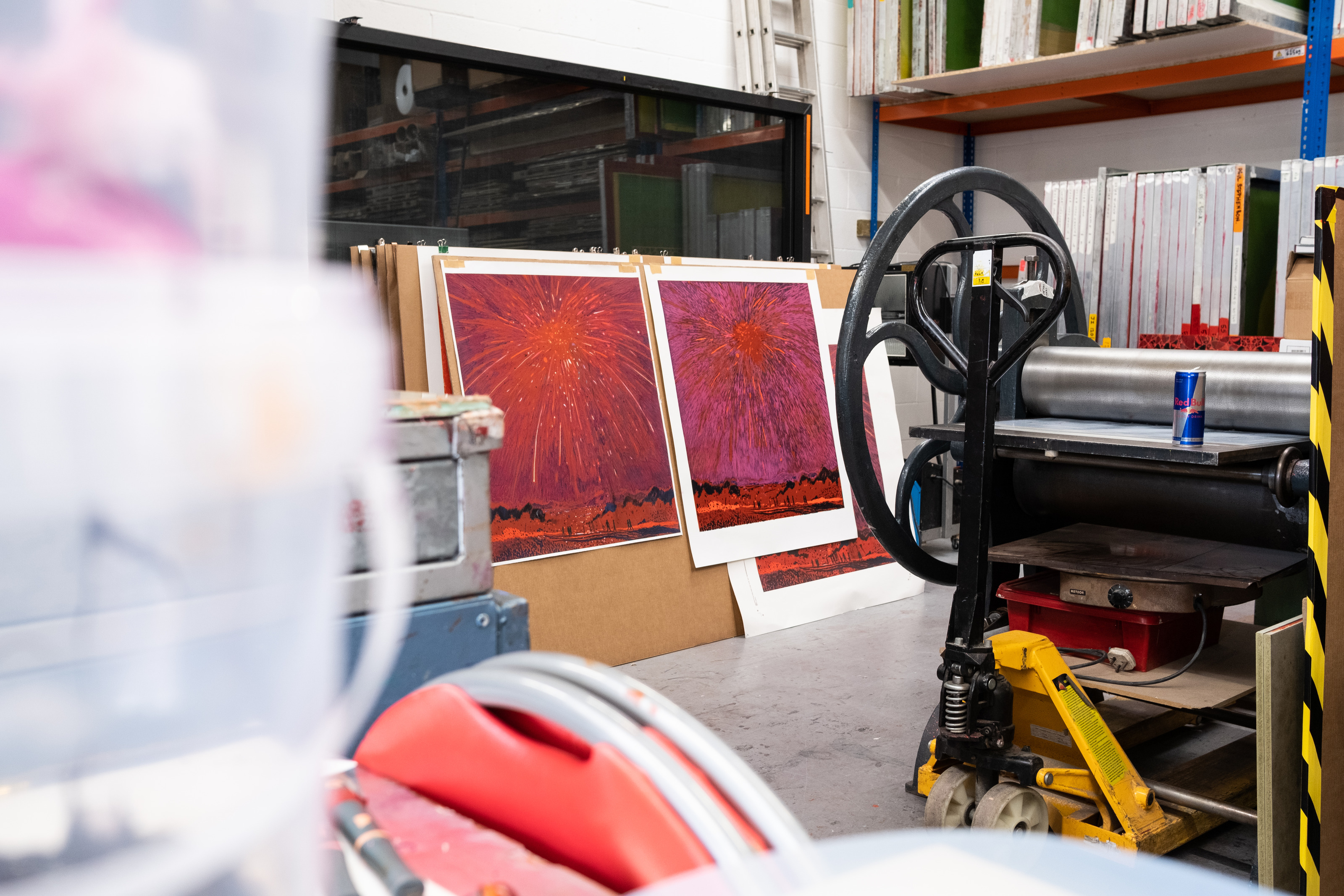 Proofs of Jules de Balincourt's firework woodcut propped in the Atelier JI studio beside a press and racks of screens.