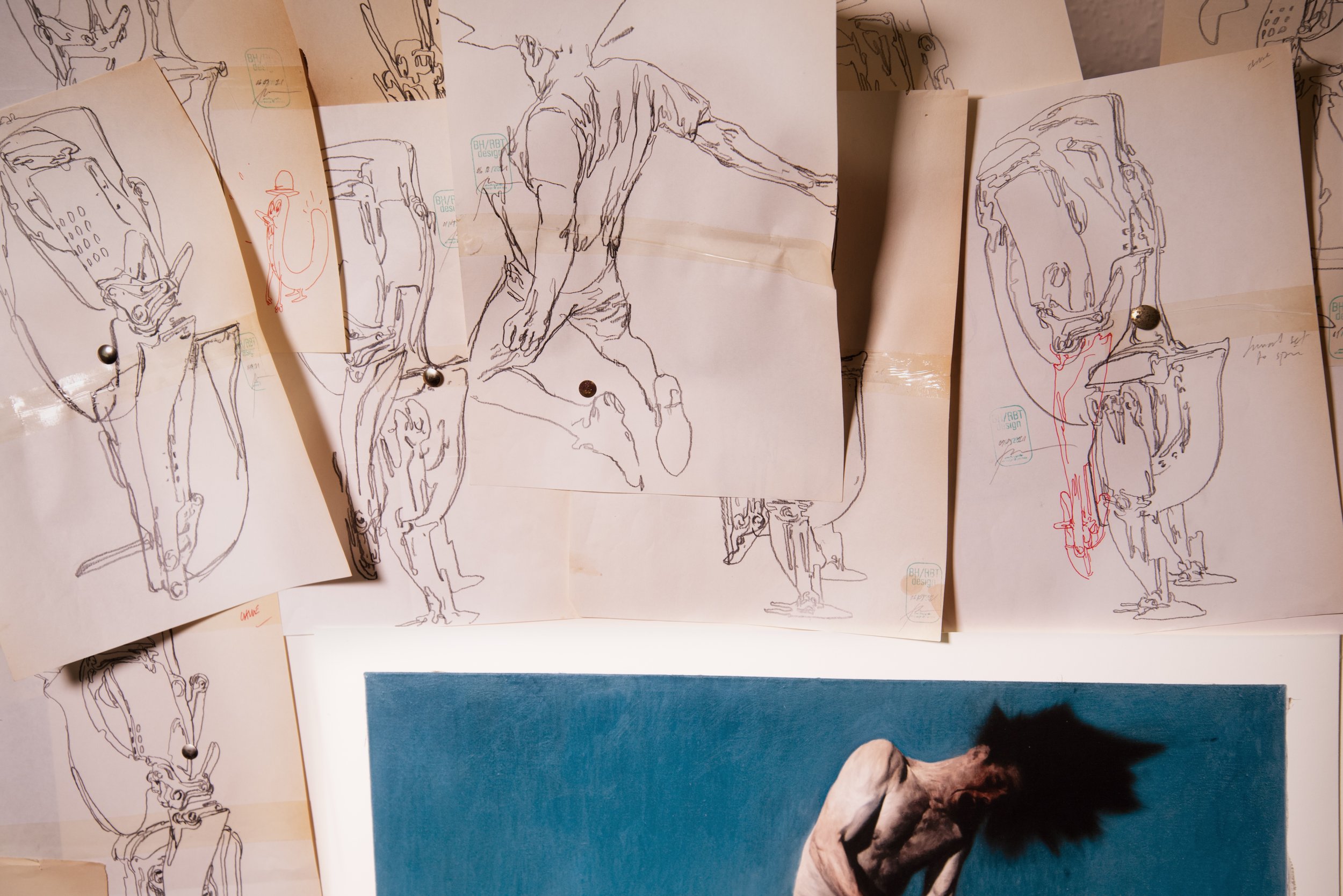 Phil Hale's studio wall: pinned pen line drawings of contorted figures around a blue painting of a man flung head-first.