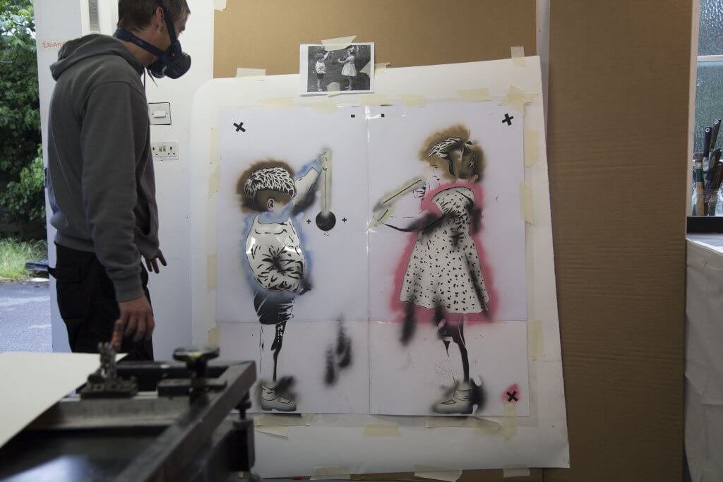 JPS in a respirator beside the taped-up 'Conker the World' stencil during printing at the Atelier JI studio.