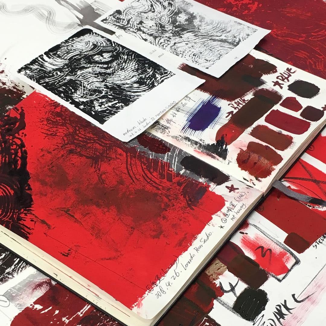 Hua Tunan's sketchbook open on a red 'Fearless' proof, with colour-test swatches, a black print reference and studio notes.