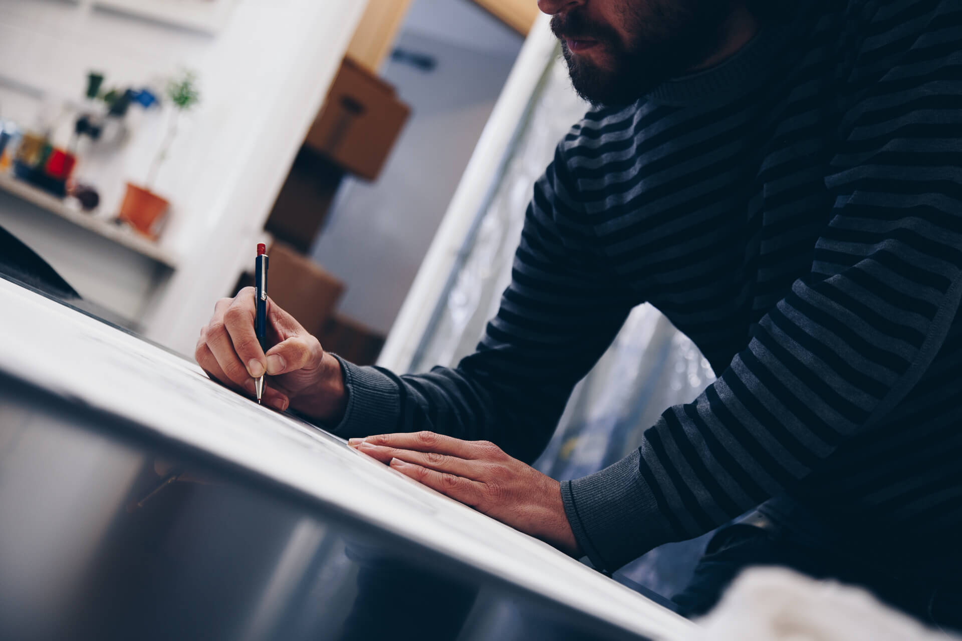 Bisser drawing fine detail onto the Migration plate with a pen at the Atelier JI studio.