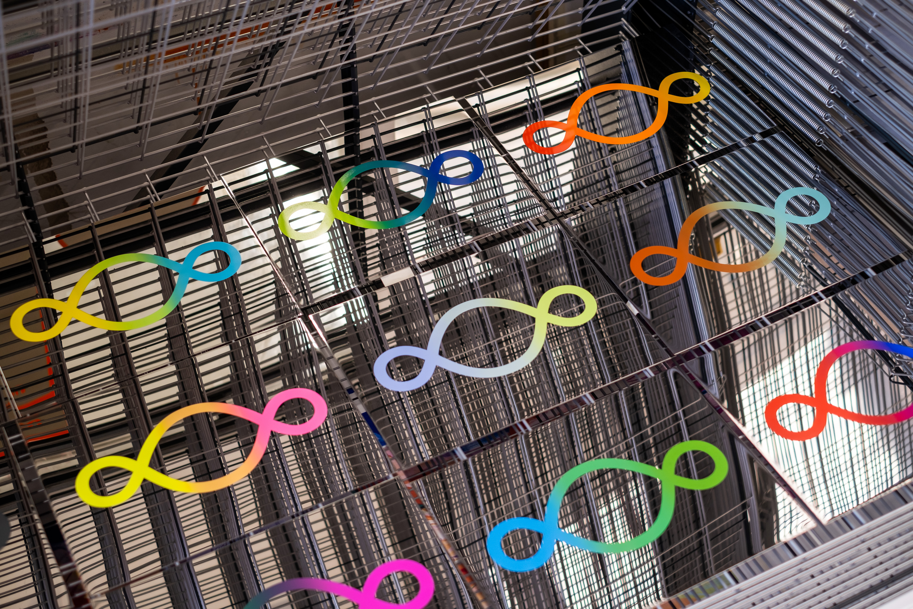 Pistoletto’s Preventive Peace Flags drying in racks at Atelier JI, gradient Third Paradise symbols on mirror reflecting the wire racks