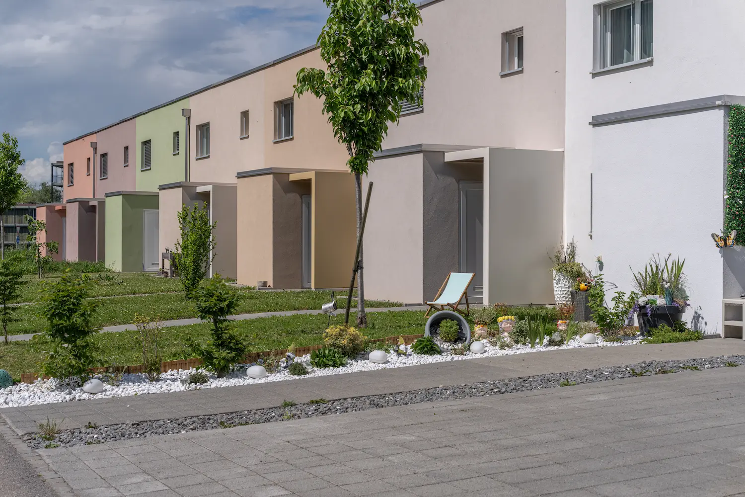 Rangée de maisons mitoyennes modernes aux façades colorées avec jardins paysagers dans le quartier Nature Parc à Monthey, photographiée par Pixera