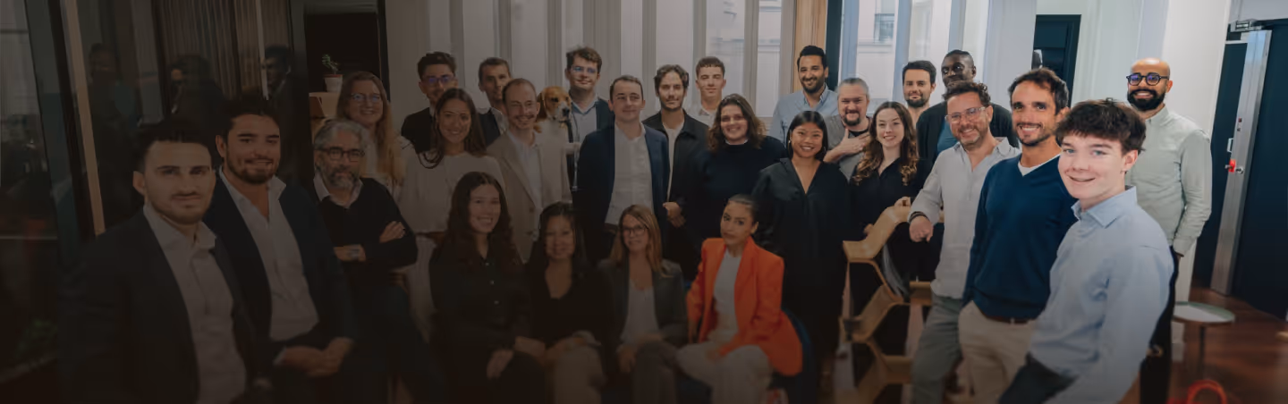 Groupe de 28 personnes souriantes en tenue professionnelle posant dans un bureau lumineux.