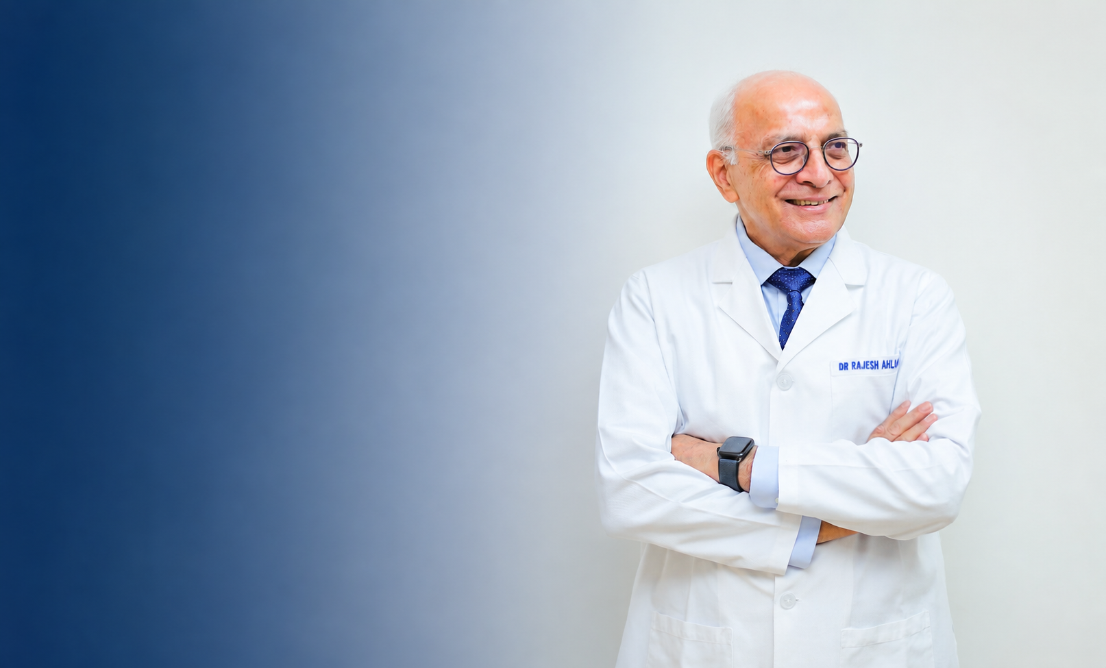 Smiling older male doctor wearing glasses and white coat with arms crossed on a gradient blue background.
