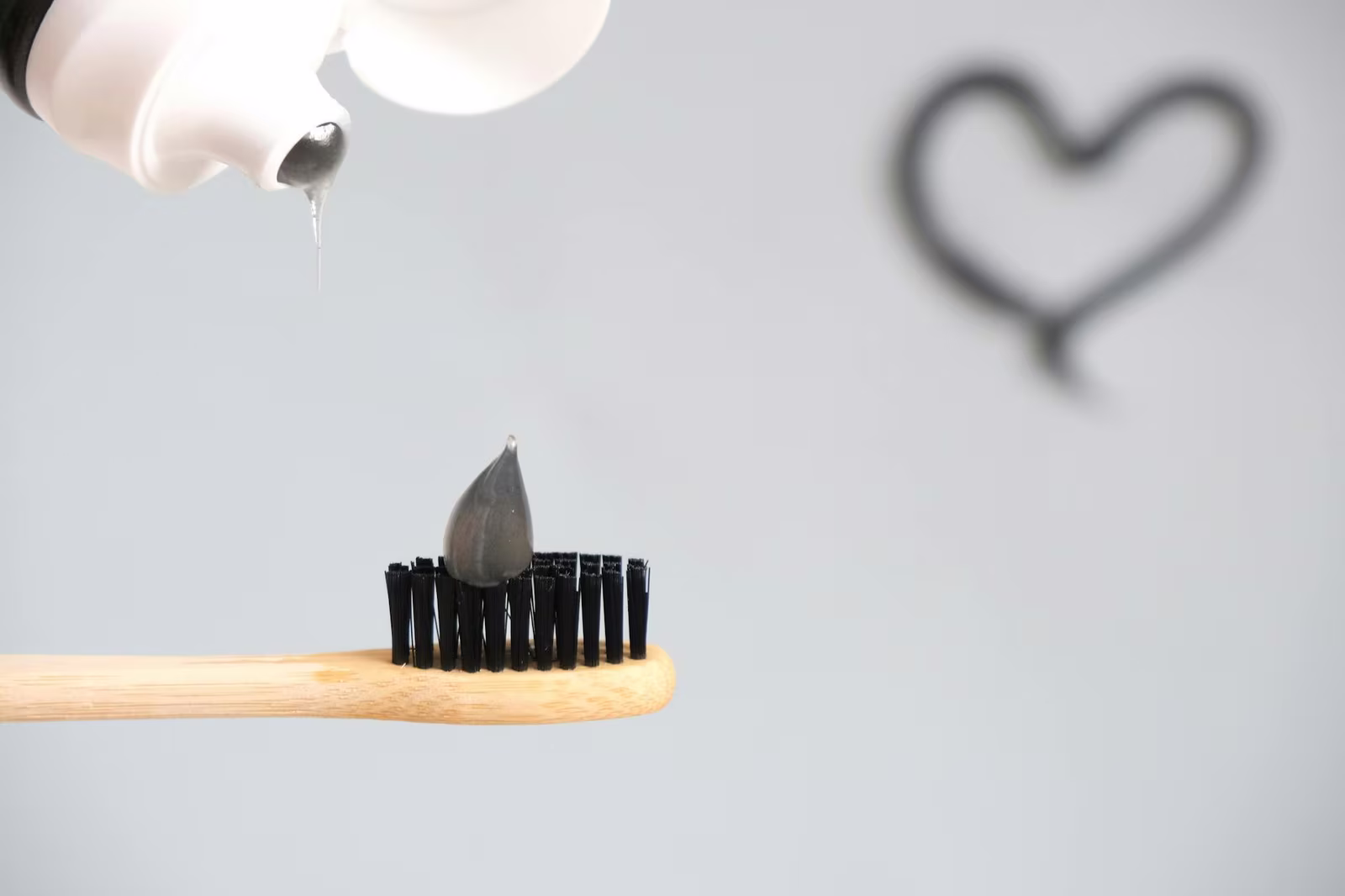 Charcoal toothpaste on a toothbrush compared with standard fluoride whitening toothpaste