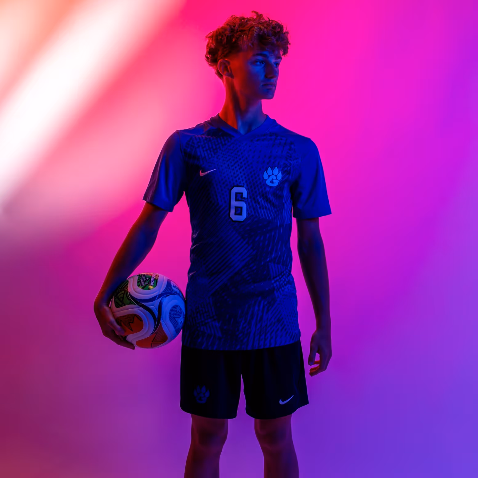 Weston Ochs in number 6 jersey holding a soccer ball against a pink and purple background.