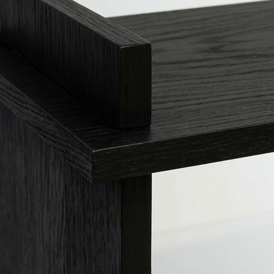 Close-up of a black wood corner joint showing the texture and grain of the wood panels.