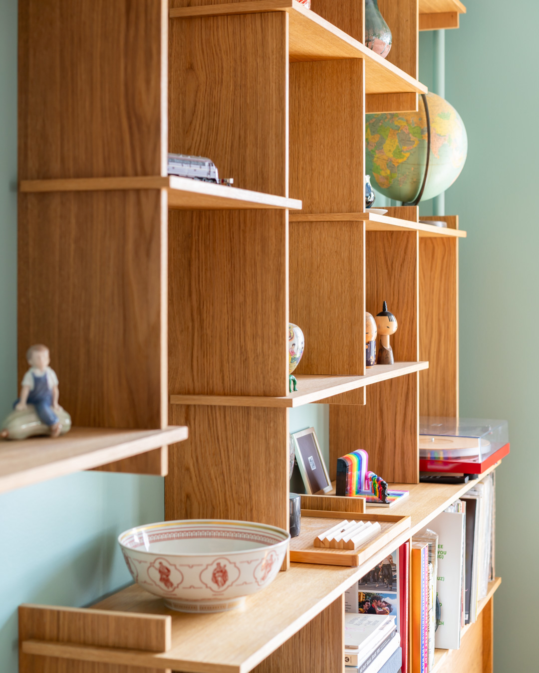 Close-up of a red lamp base on a wooden shelf with books in the background.
