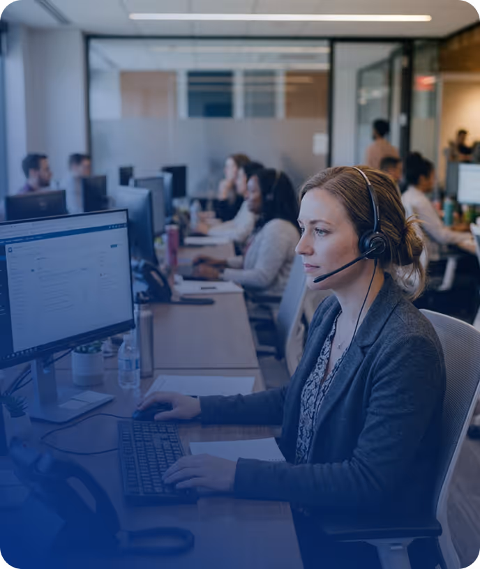 Customer support agent wearing a headset working at a computer in a modern call center – Urssaf Compliant