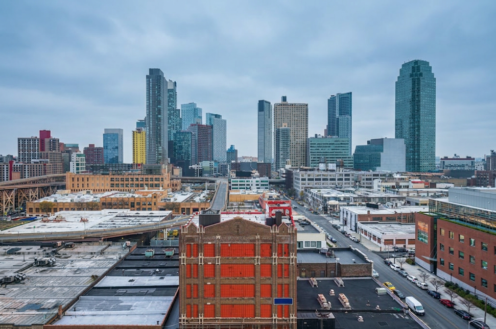 City skyline with tall buildings under a cloudy sky and older brick buildings in the foreground.
