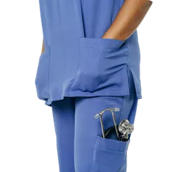 Person wearing blue medical scrubs with stethoscope in pocket and hand in upper pocket.
