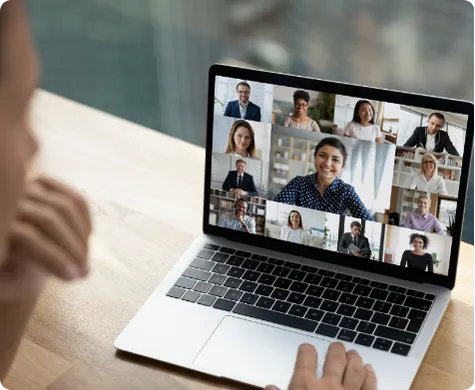 Person attending a virtual video conference on a laptop with multiple participants visible.
