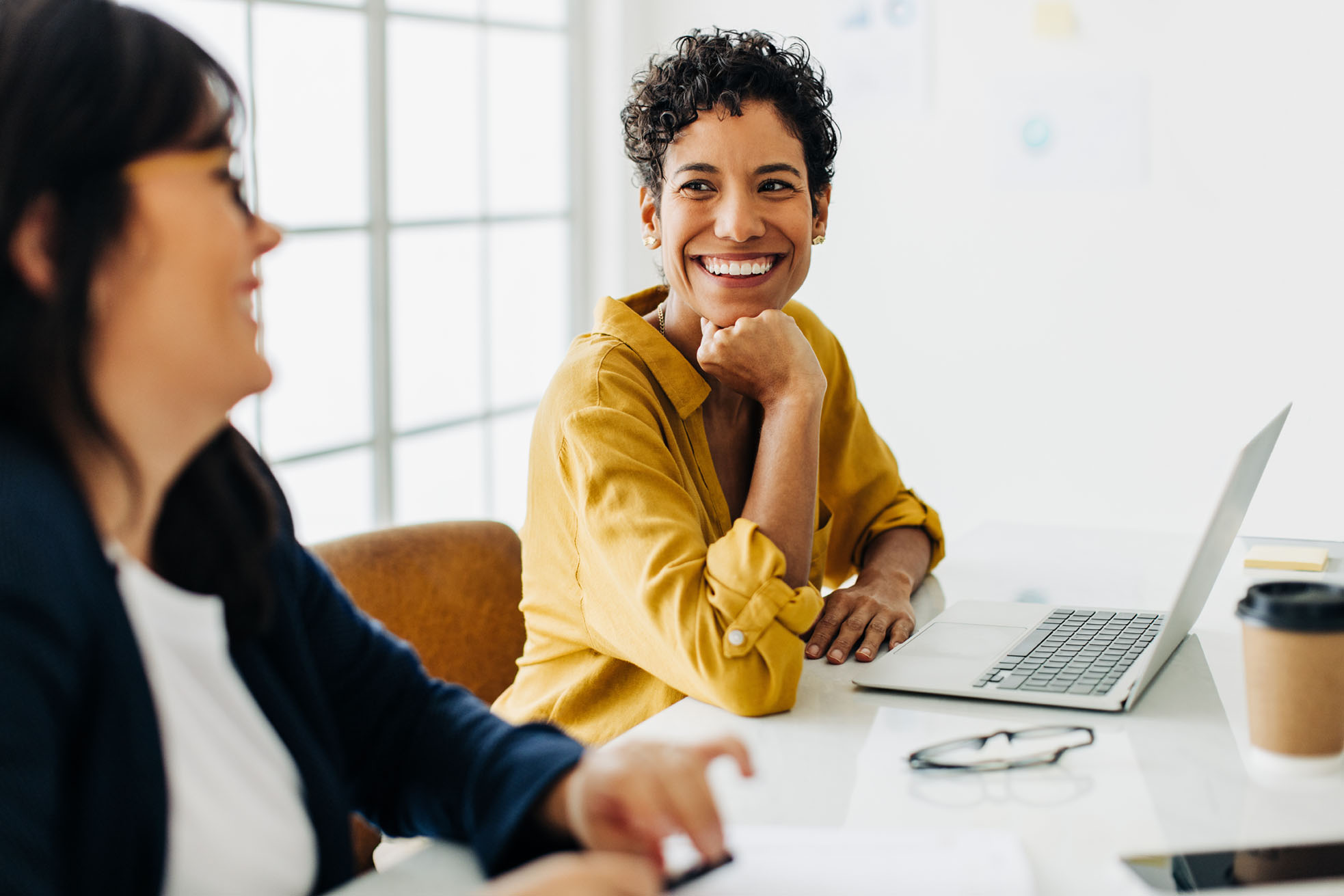 Two women talking and laughing in a co-working space